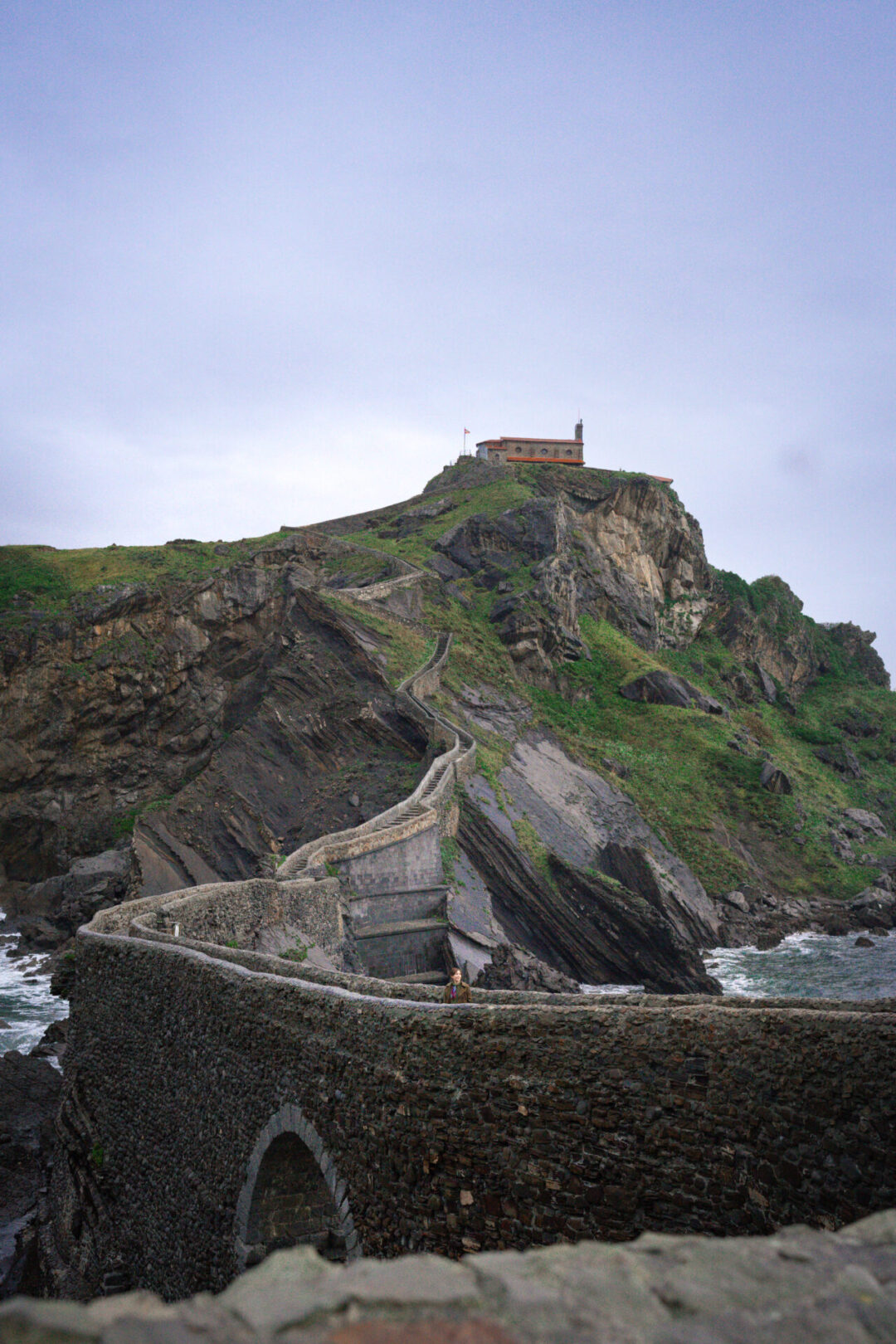 Travel Blogger Jordan Gassner standing along the pathway leading up to San Juan de Gaztelugatxe in Spain