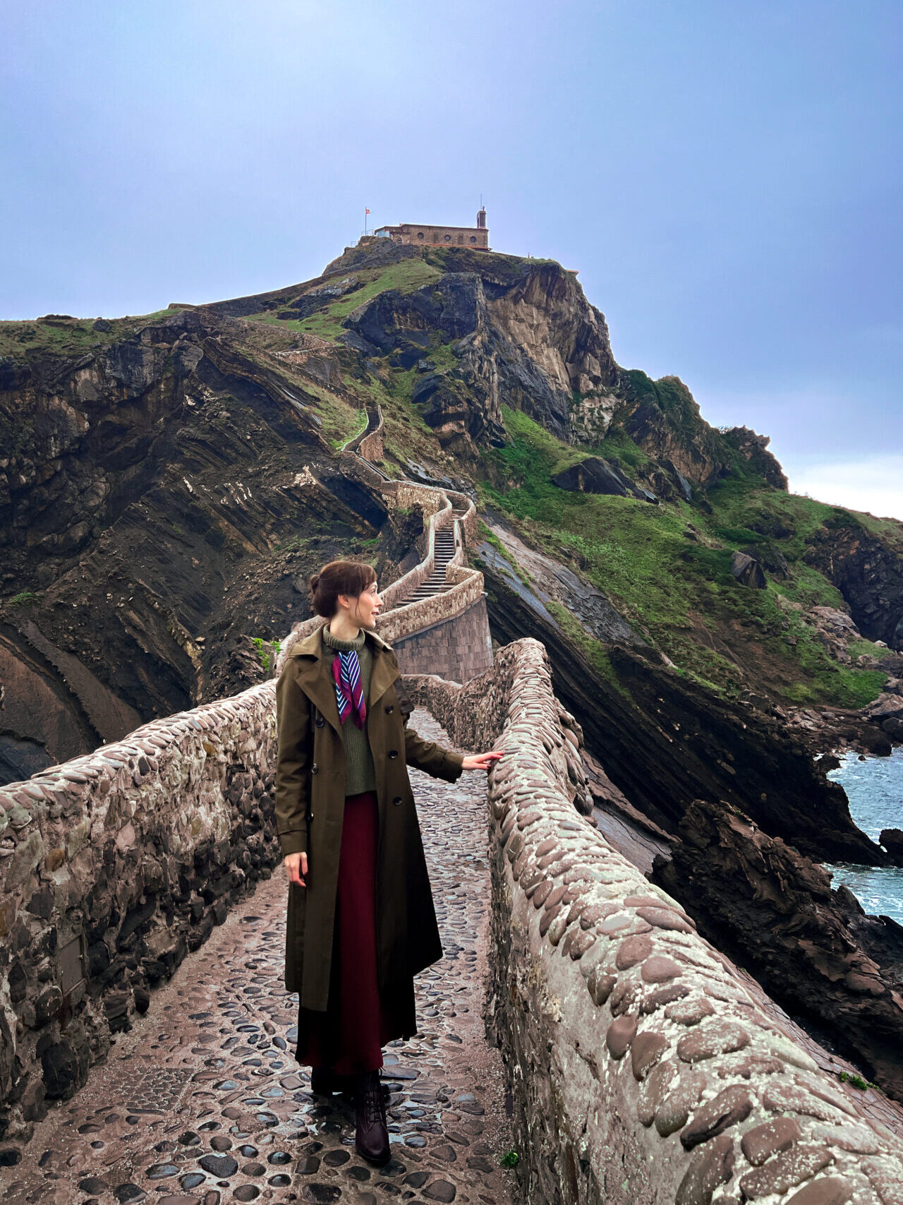 Travel Blogger Jordan Gassner looking toward the sea from the stone stairway to San Juan de Gaztelugatxe in Spain