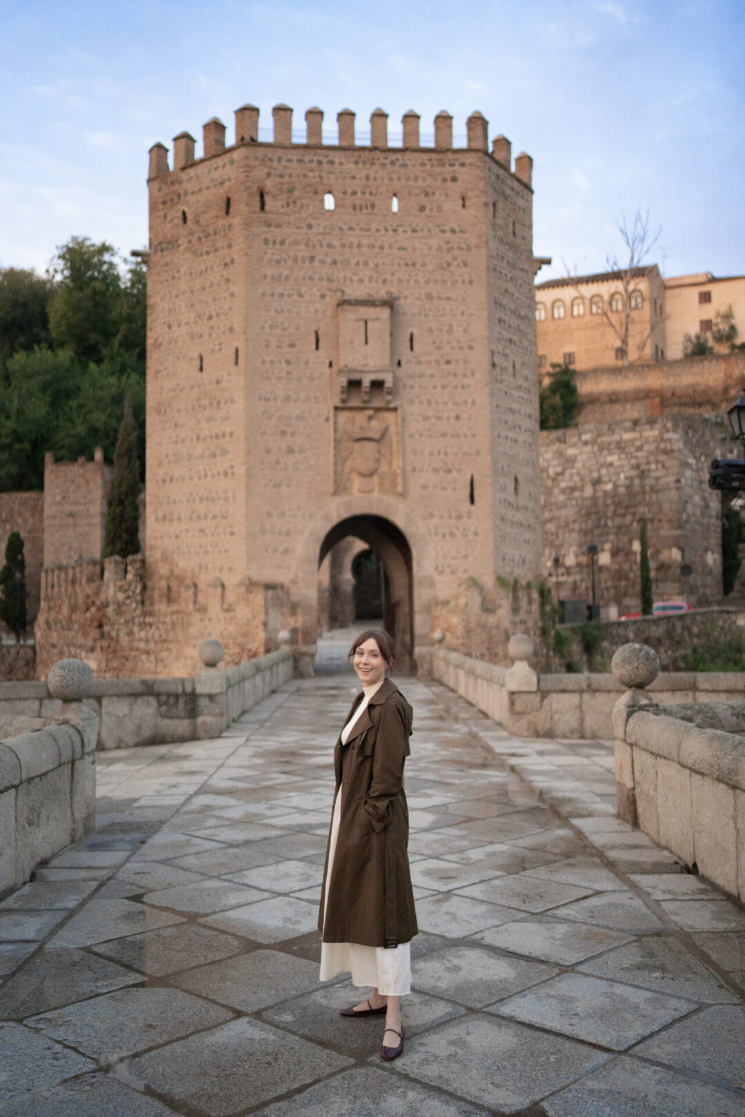 Travel Blogger Jordan Gassner standing and smiling on top of Alcantara Bridge just after sunrise in Toledo, Spain