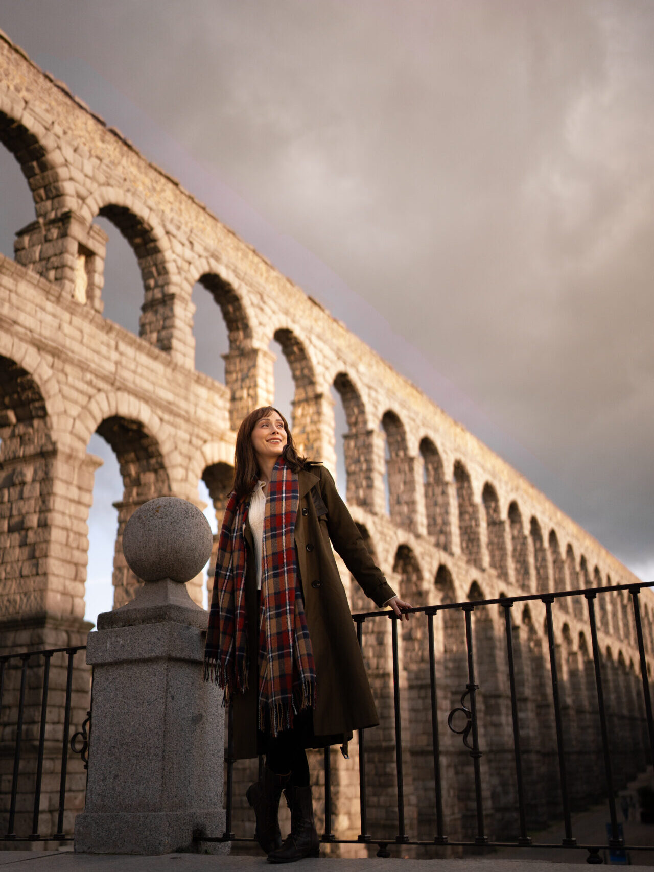 Travel Blogger Jordan Gassner smiling from a lookout with a view of the Roman aqueduct in Segovia, Spain