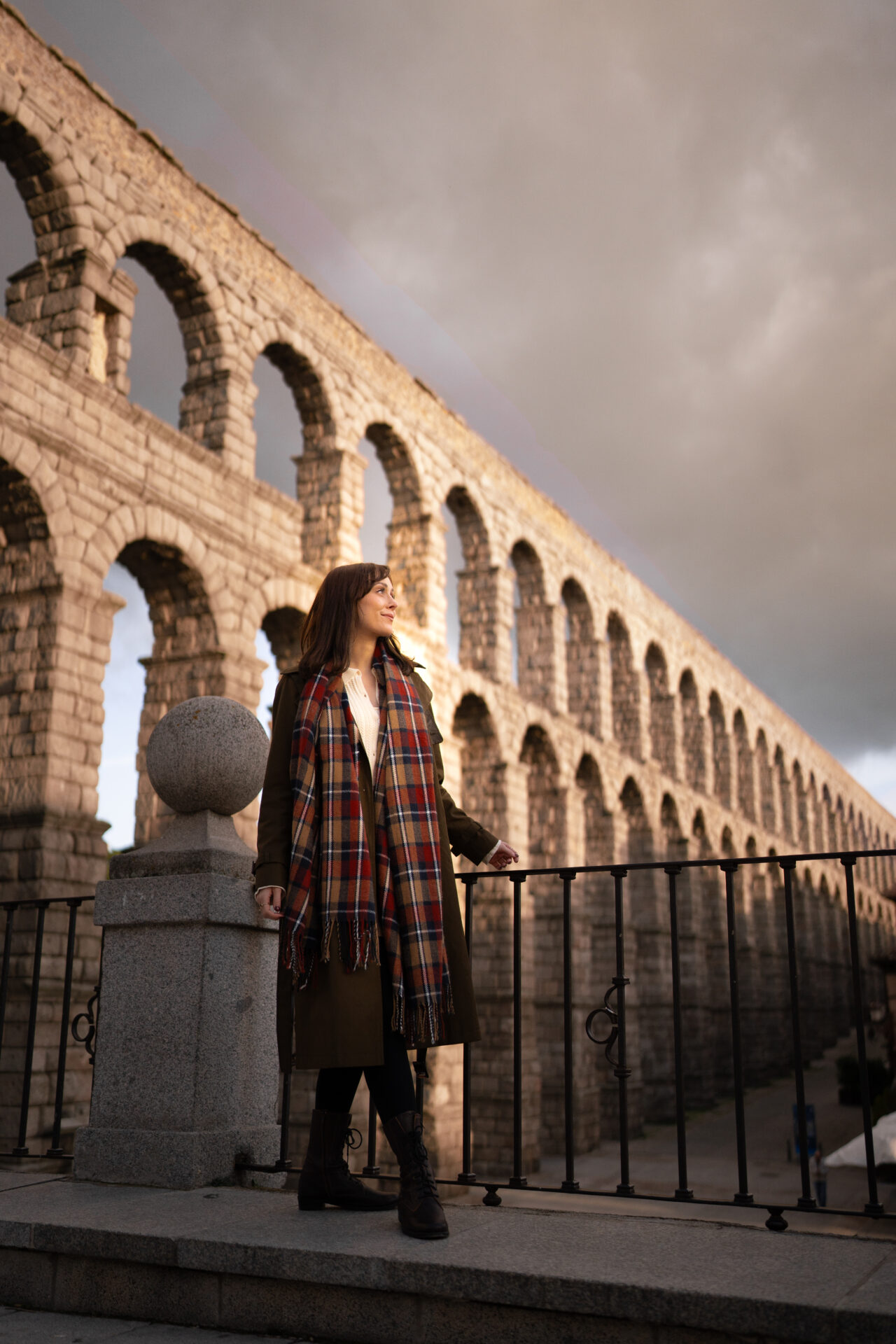 Travel Blogger Jordan Gassner walking along a lookout with a view of the Roman aqueduct in Segovia, Spain