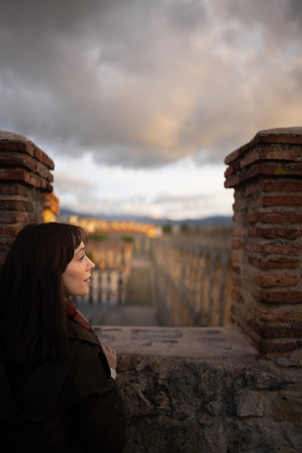 Travel Blogger Jordan Gassner looking right from a lookout in Segovia, Spain - the city's famous Roman aqueduct just in front of her