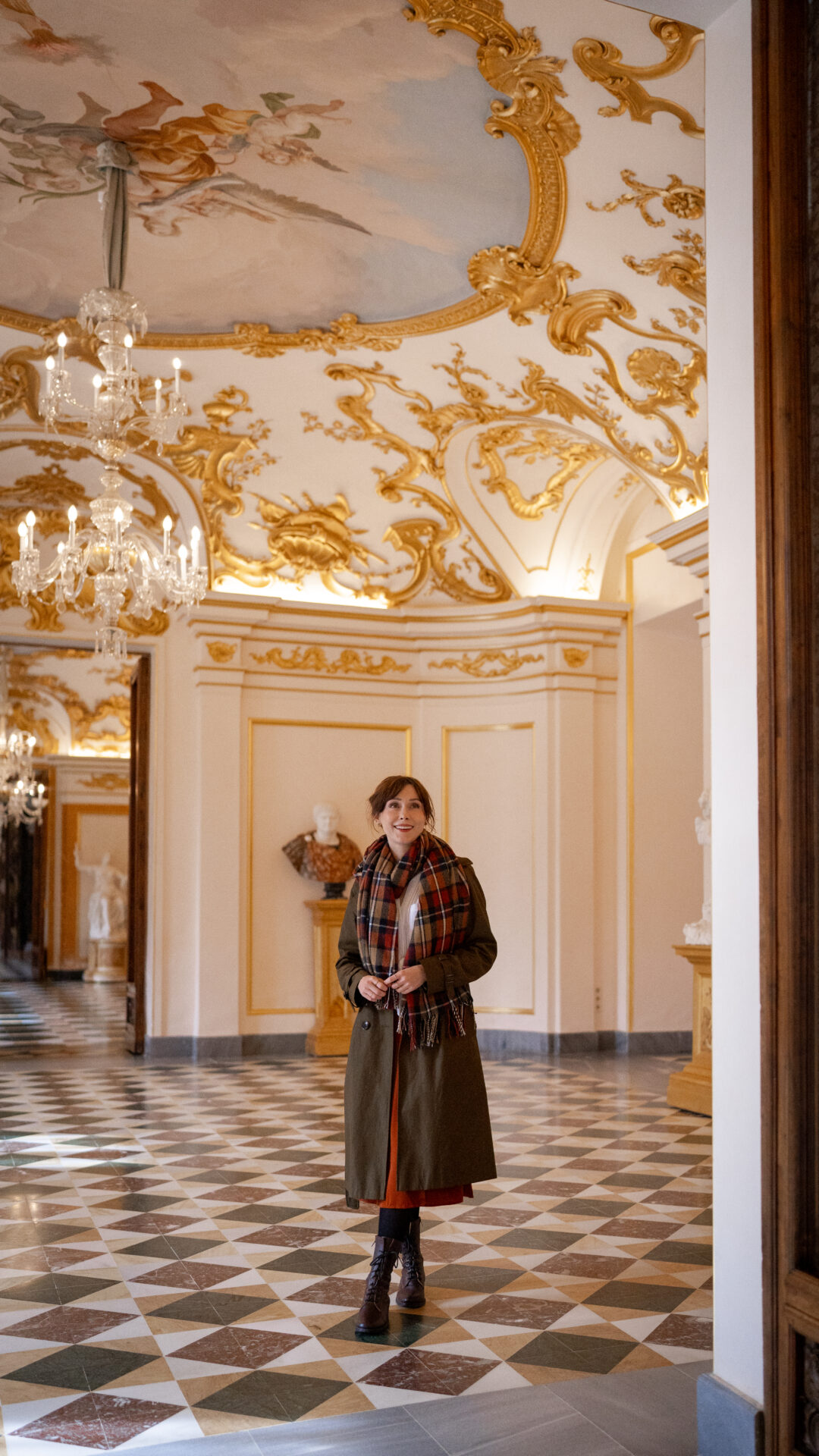 Travel Blogger Jordan Gassner smiling inside an empty, yet grand hallway the Royal Palace of La Granja of San Ildefonso in Segovia, Spain