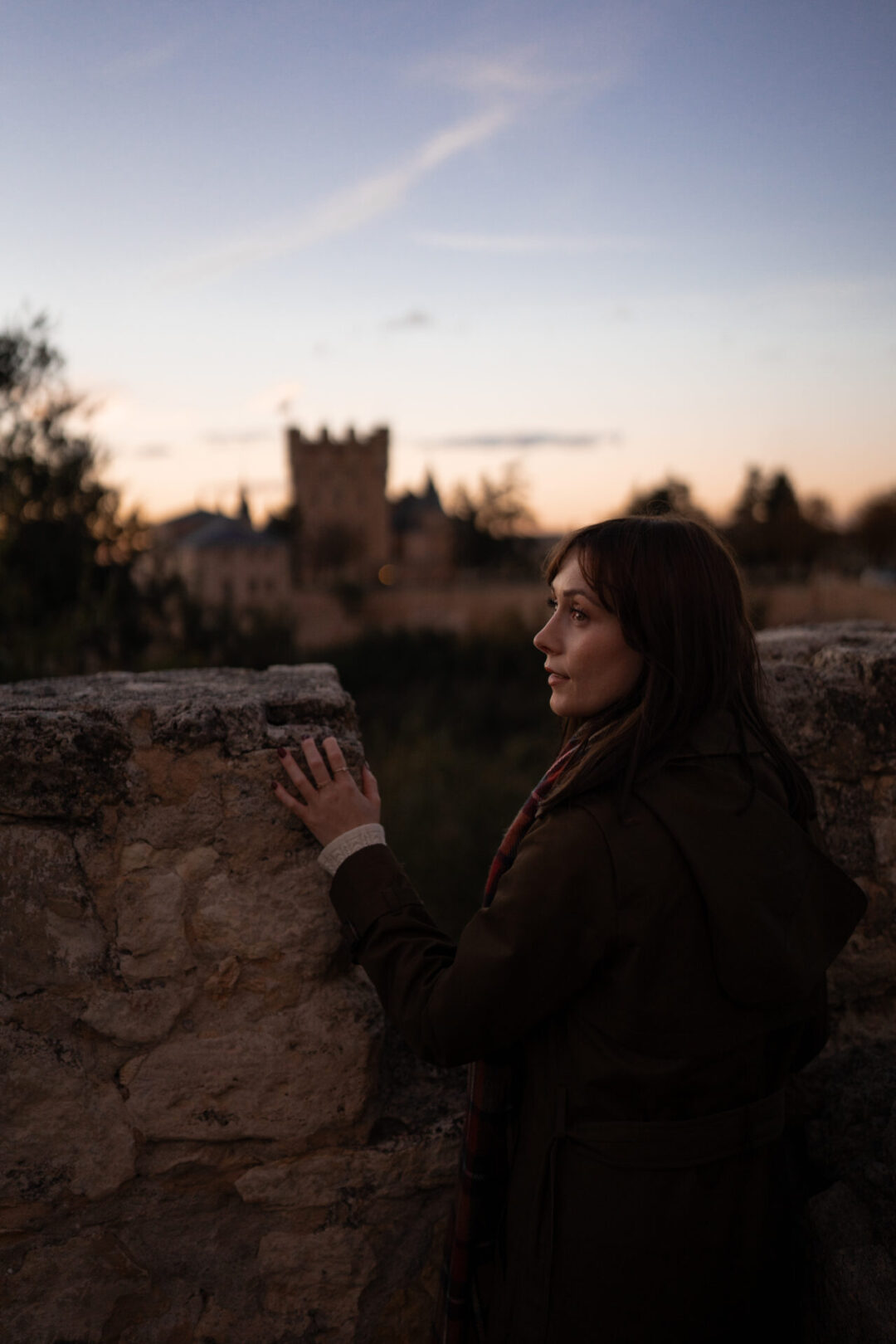 Travel Blogger Jordan Gassner looking over her shoulder from Mirador de la Pradera de San Marcos with a view of the Alcazar in the background in Segovia, Spain
