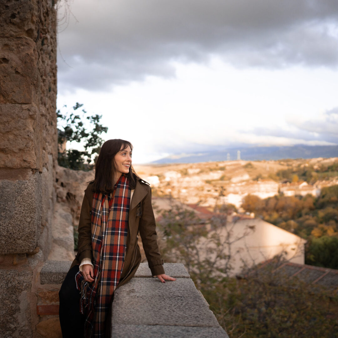 Travel Blogger Jordan Gassner smiling while sitting on a balcony overlooking Segovia, Spain