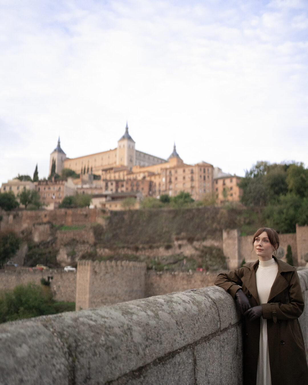 Travel Blogger Jordan Gassner looking out from the Bridge of Alcantara in Toledo, Spain - the view of the famous Alcazar in the background