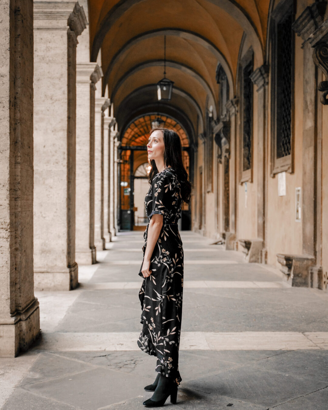 Travel Blogger Jordan Gassner looking up from under a colonnade in Rome, Italy