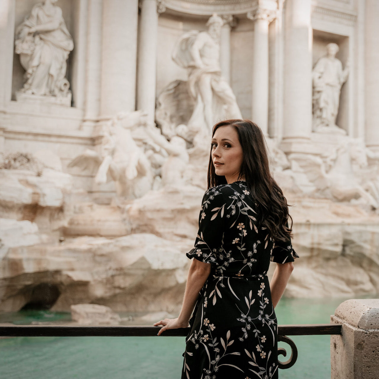 Travel Blogger Jordan Gassner looking over her shoulder at the Trevi Fountain in Rome, Italy