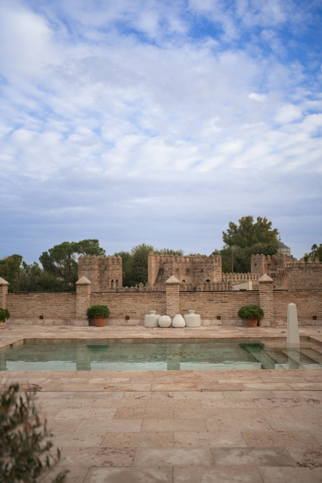 The outdoor pool at Hotel Hacienda del Cardinal in front of a medieval wall in the Old Town of Toledo, Spain