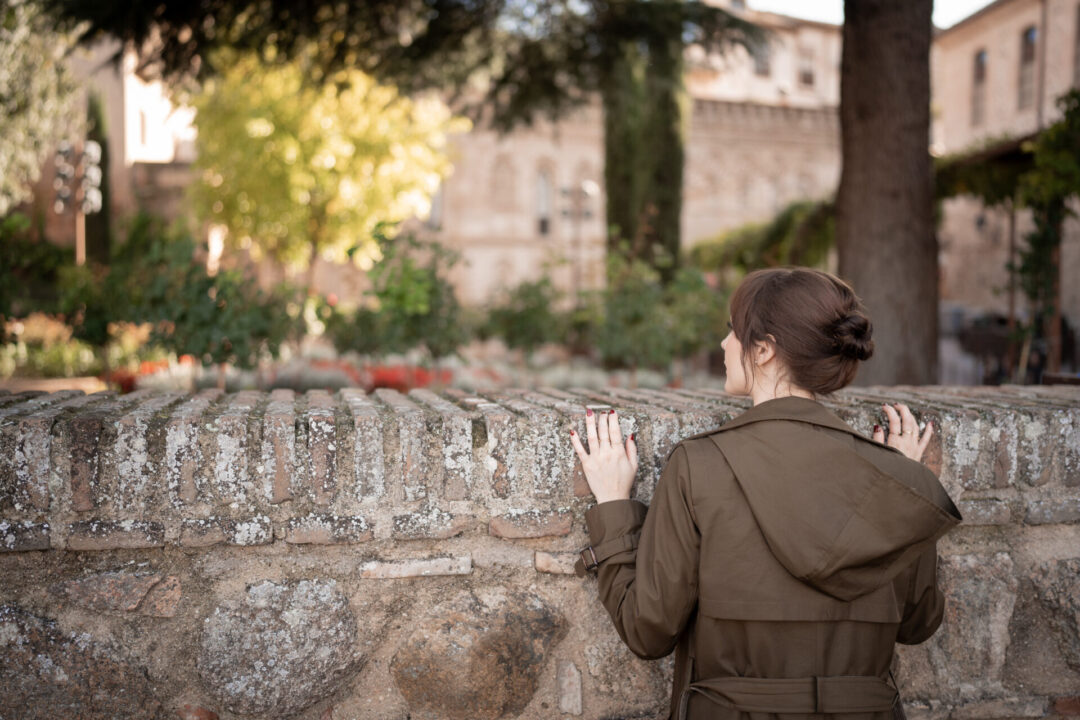 Travel Blogger Jordan Gassner peering over a wall toward the Mosque of Christ of the Light in Toledo, Spain