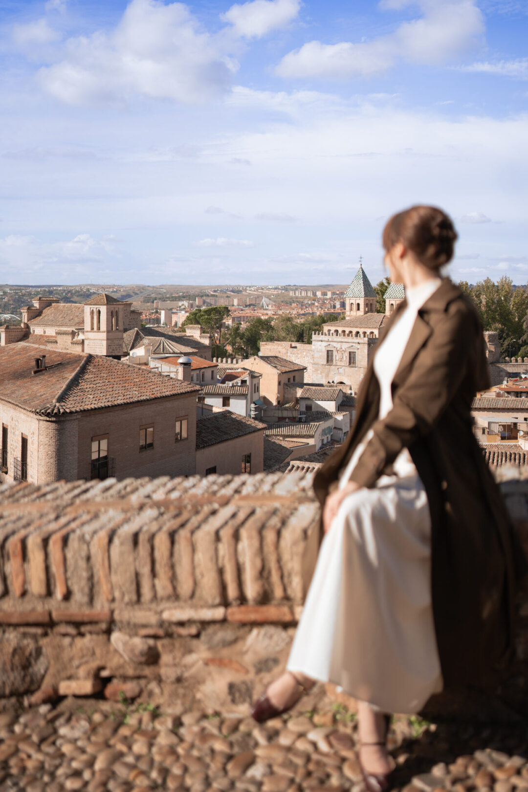 Travel Blogger Jordan Gassner looking out at Toledo, Spain from a hilltop viewpoint on a clear blue day