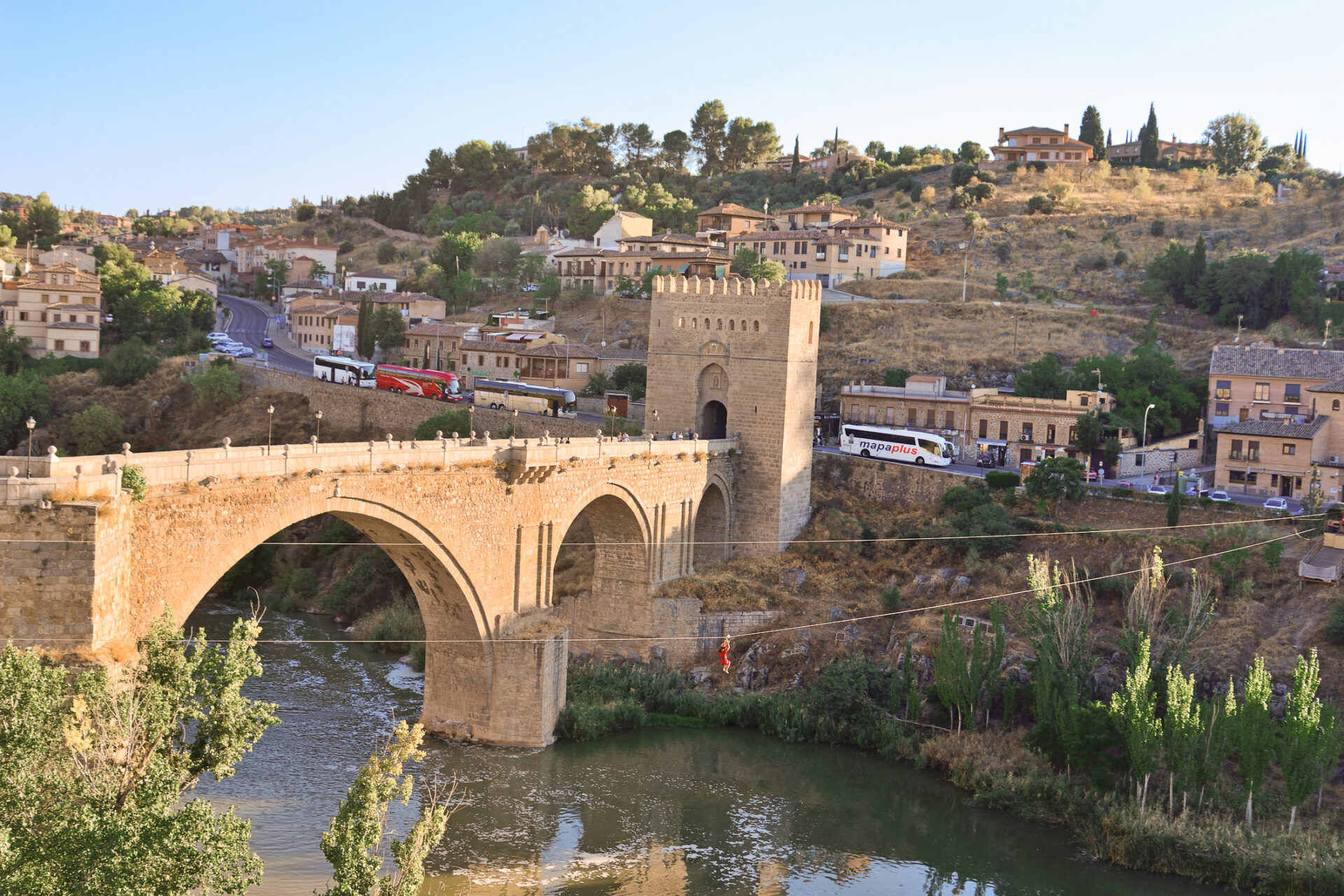 People ziplining near the San Martin Bridge in Toledo, Spain