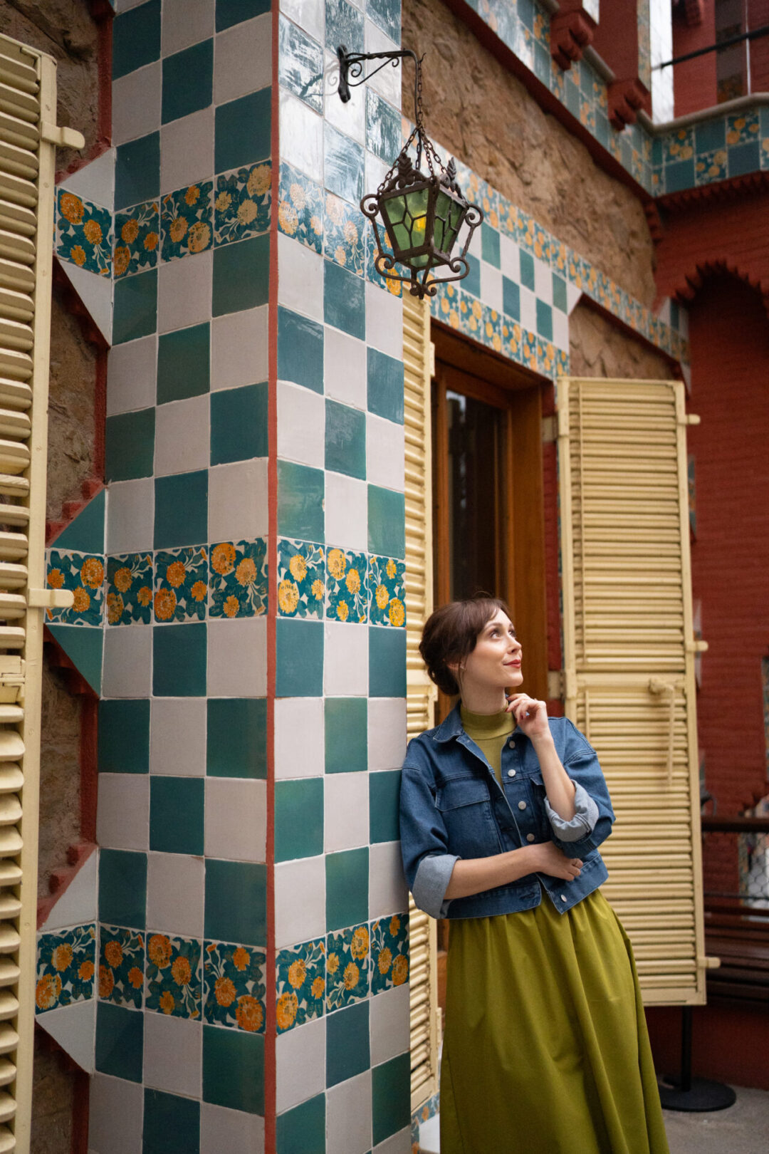 Travel Blogger Jordan Gassner leaning against green, orange, and white ceramic tiles on the walled rooftop of Casa Vicens in Barcelona, Spain