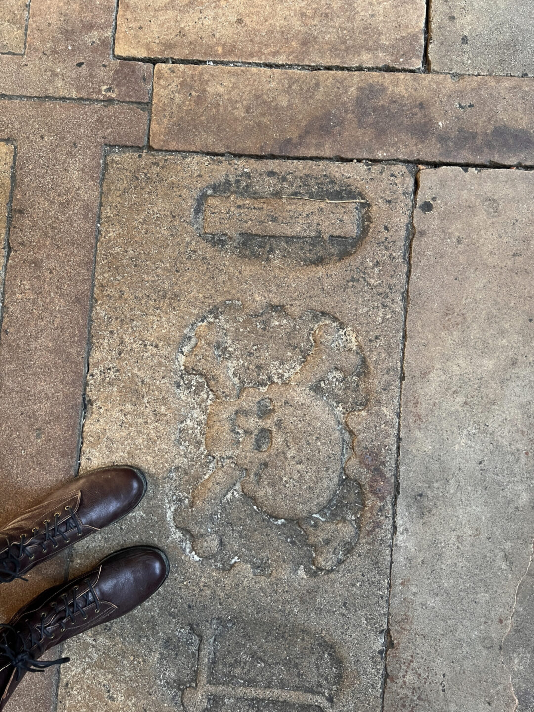 Travel Blogger Jordan Gassner standing over an unlucky skull and crossbones carving in the floor of the cloister at Barcelona Cathedral in Spain