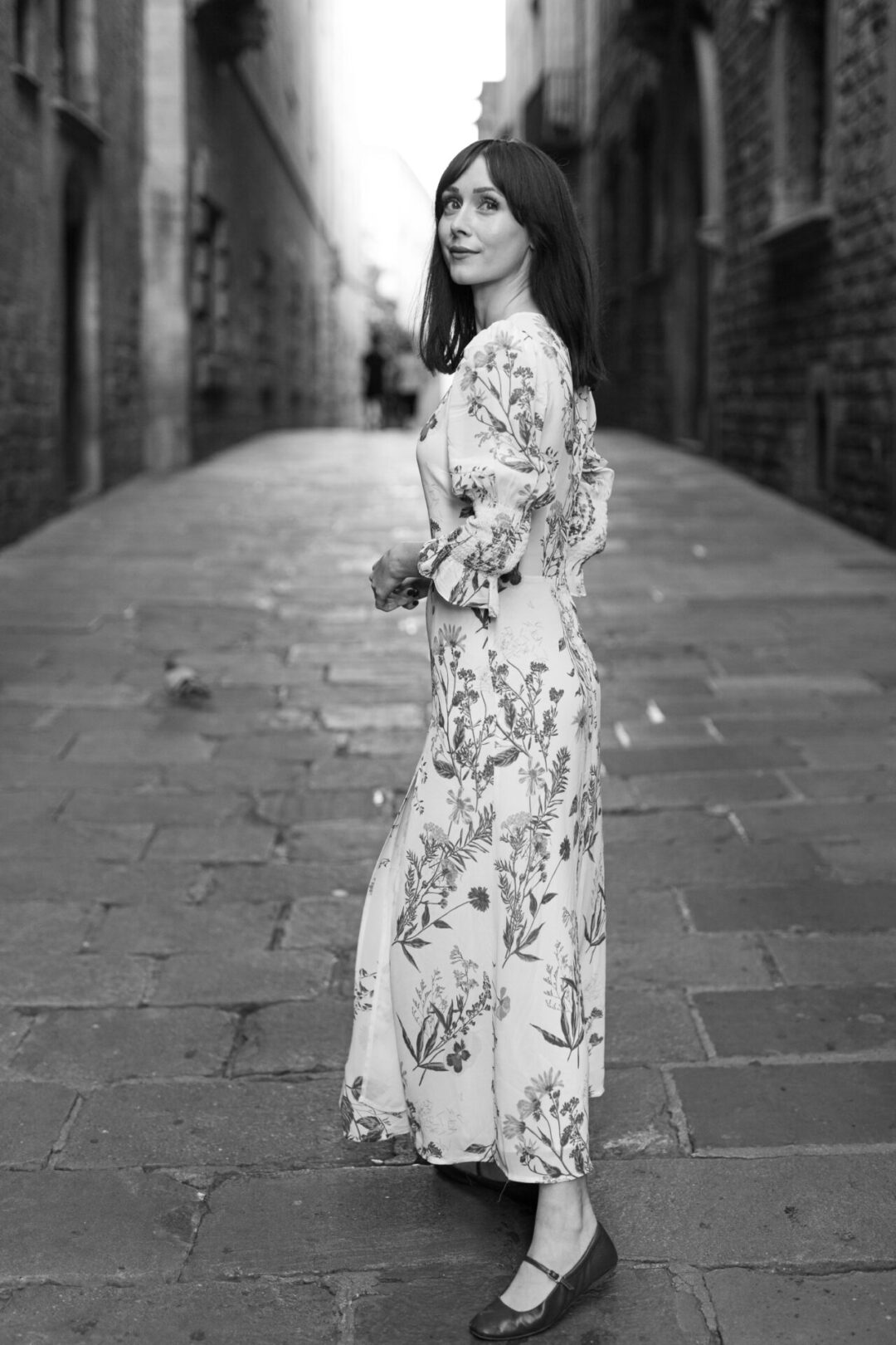 Travel Blogger Jordan Gassner peering over her shoulder while walking along the streets of Barcelona’s Gothic Quarter