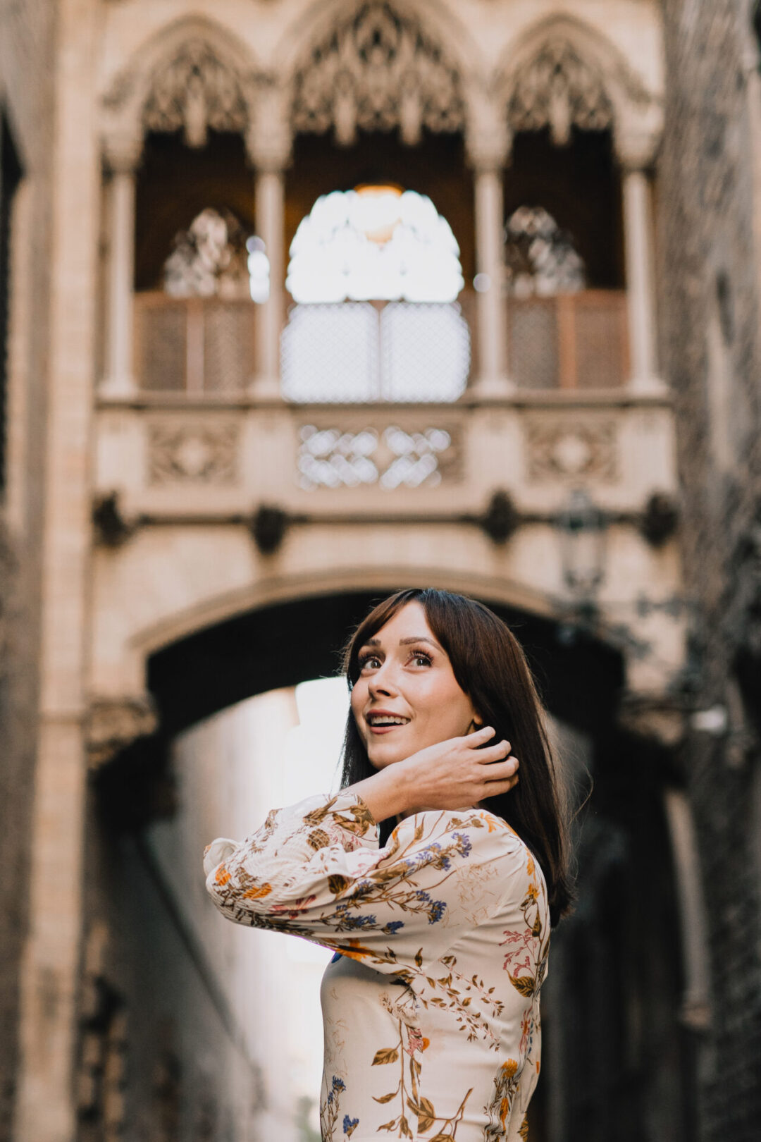 First Time in Barcelona: Travel Blogger Jordan Gassner smiling from beneath Career del Bisbe, a Neo-Gothic bridge in Barcelona’s Gothic Quarter
