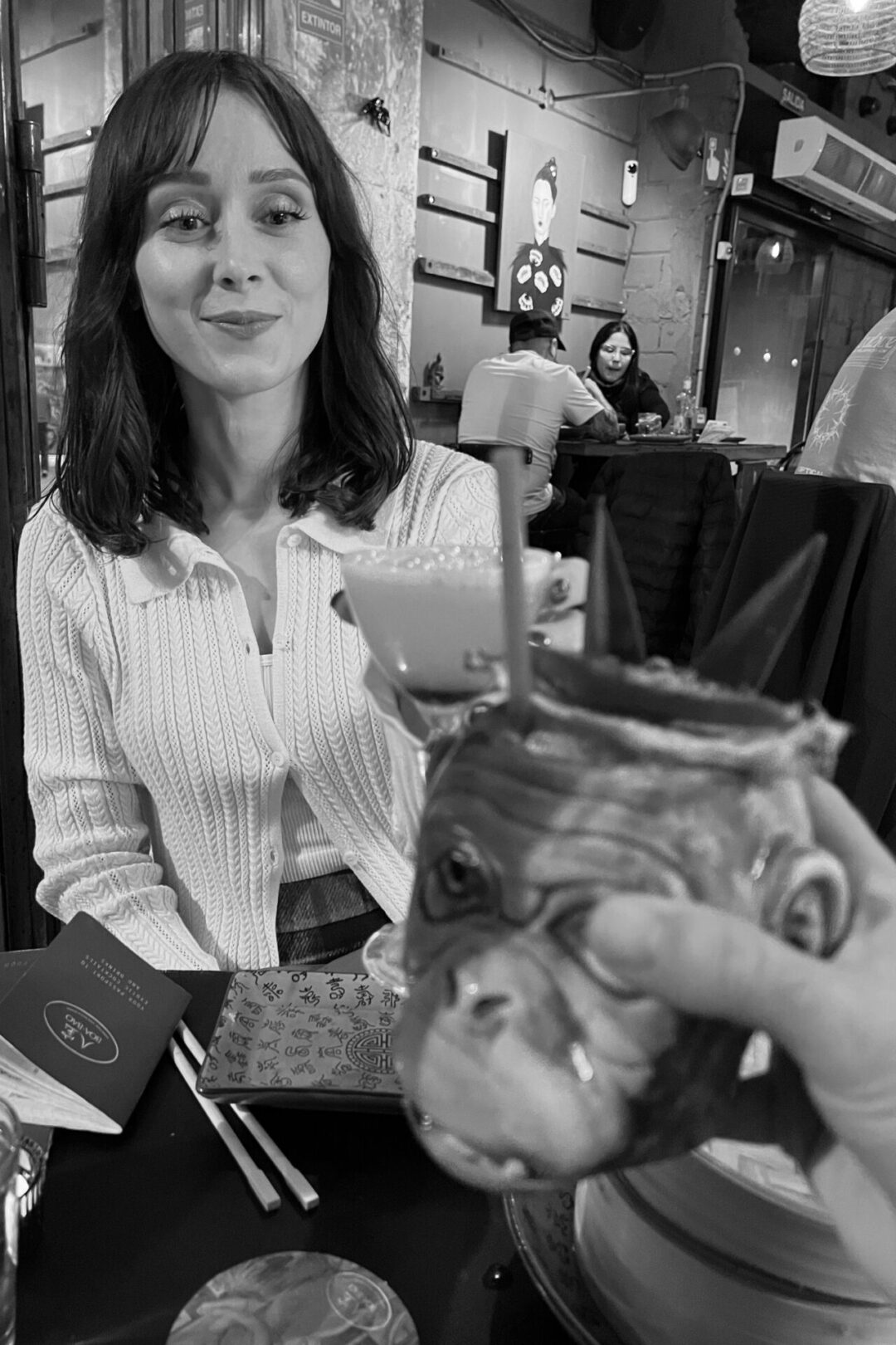 Travel Blogger Jordan Gassner cheers-ing with someone holding a monkey-shaped cocktail glass in Spain