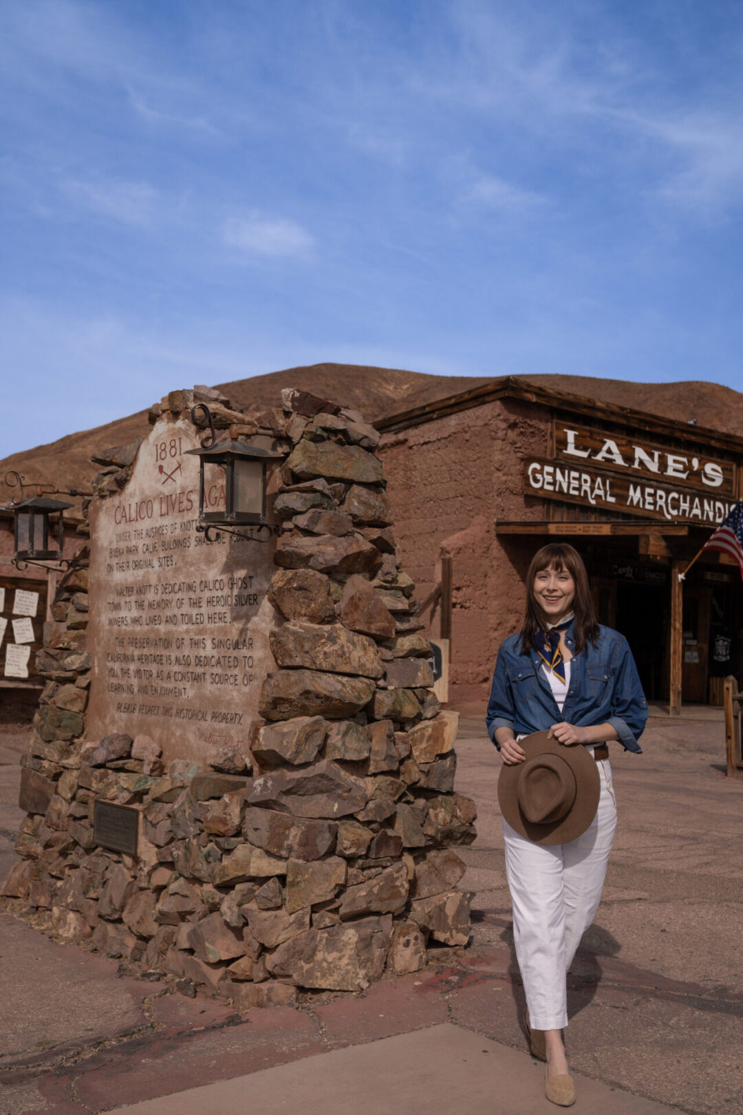 Travel Blogger Jordan Gassner walking and smiling in front of Lane's General Merchandise store at Calico Ghost Town in California