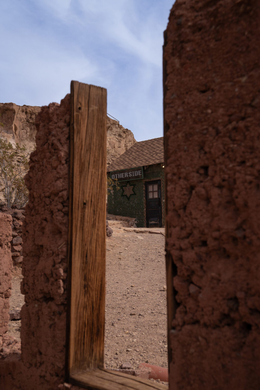 The view of a house made of recycled bottles from a former doorway at Calico Ghost Town in California