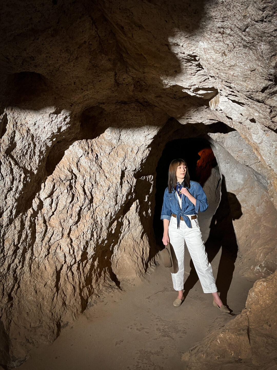 Travel Blogger Jordan Gassner standing inside a dimly lit tunnel at Calico Ghost Town's Maggie Mine in California