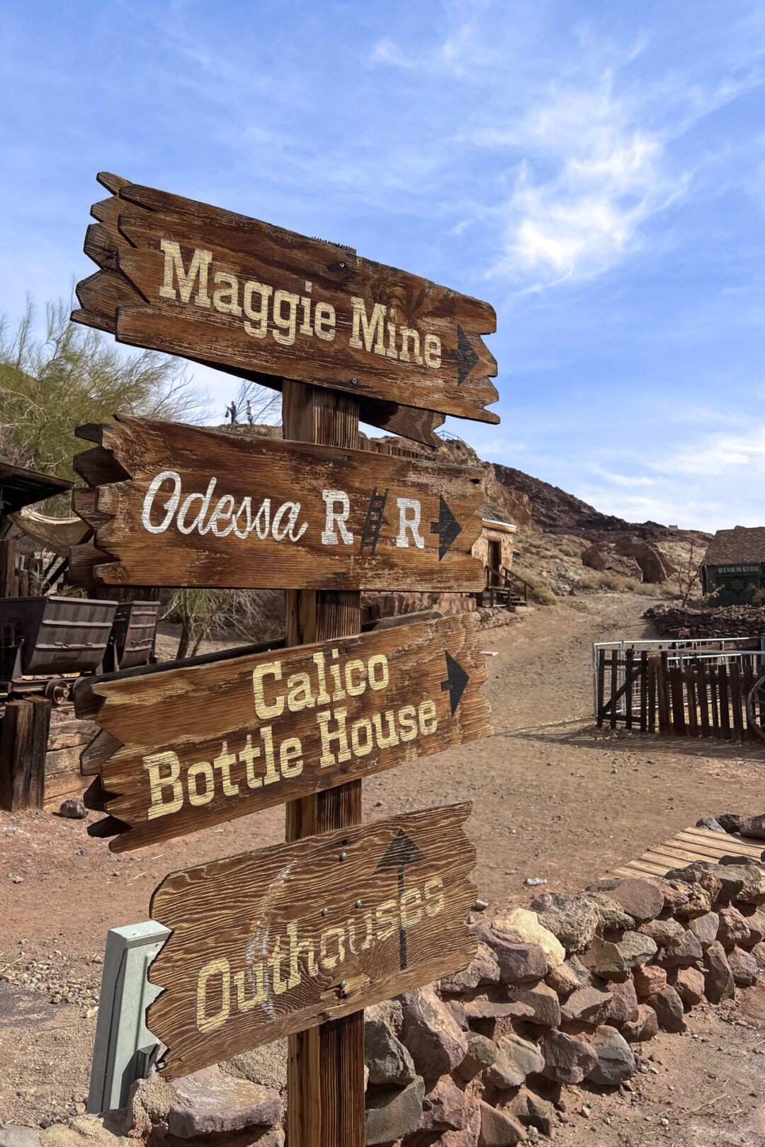 A wooden sign post with arrows to town attractions inside Calico Ghost Town in California