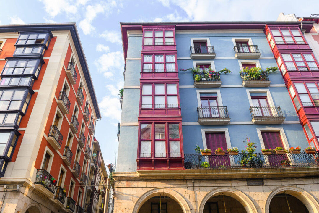 An orange painted building next to a blue building with purple terraces in Bilbao's old town