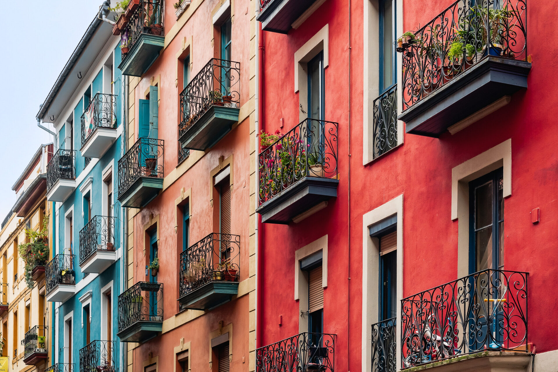 Wrought-iron terraces along red, salmon, teal and yellow vintage buildings in Old Town Bilbao, Spain