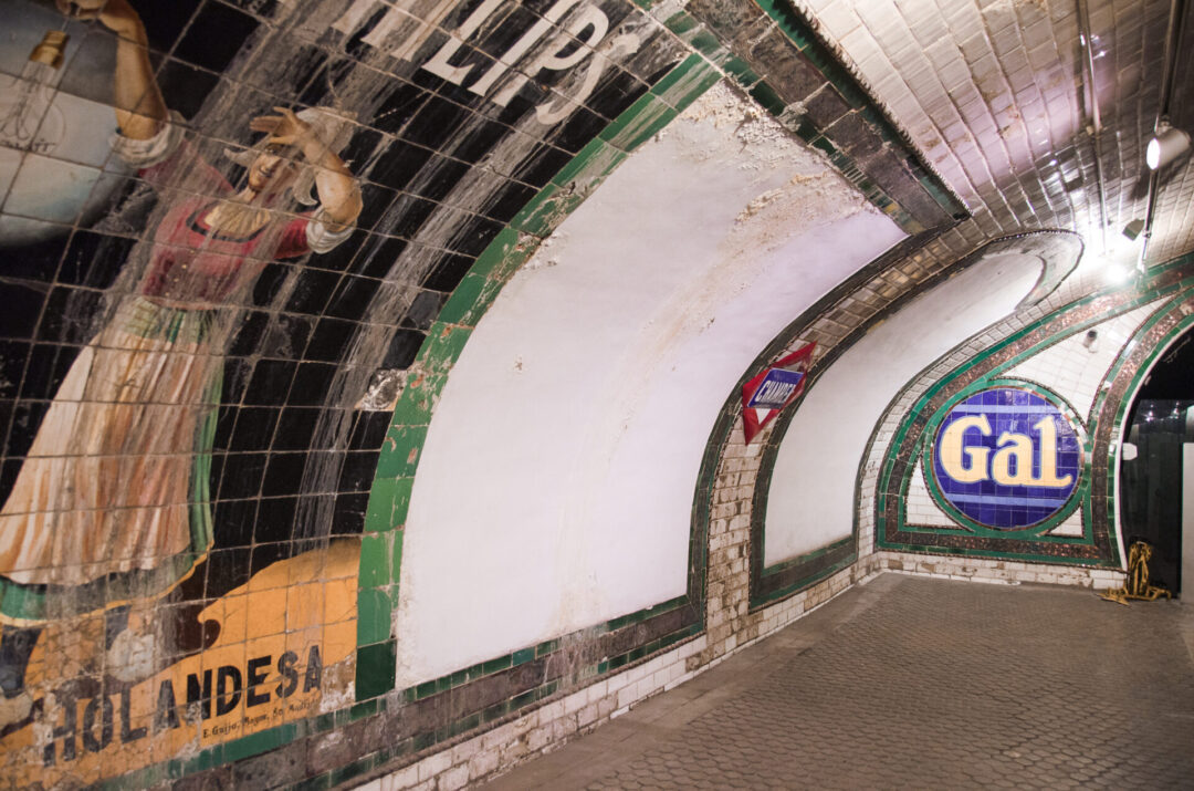 A vintage advertisement reading "Holandesa" with a painted traditional milk maid on it at Chamberi Ghost Station in Madrid, Spain