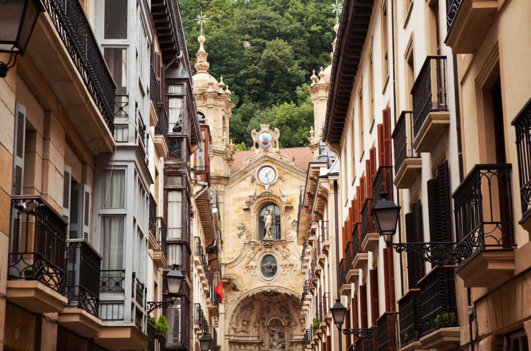 A view of an old church along an avenue of historic multi-family homes in San Sebastian, Spain - a day trip from Bilbao