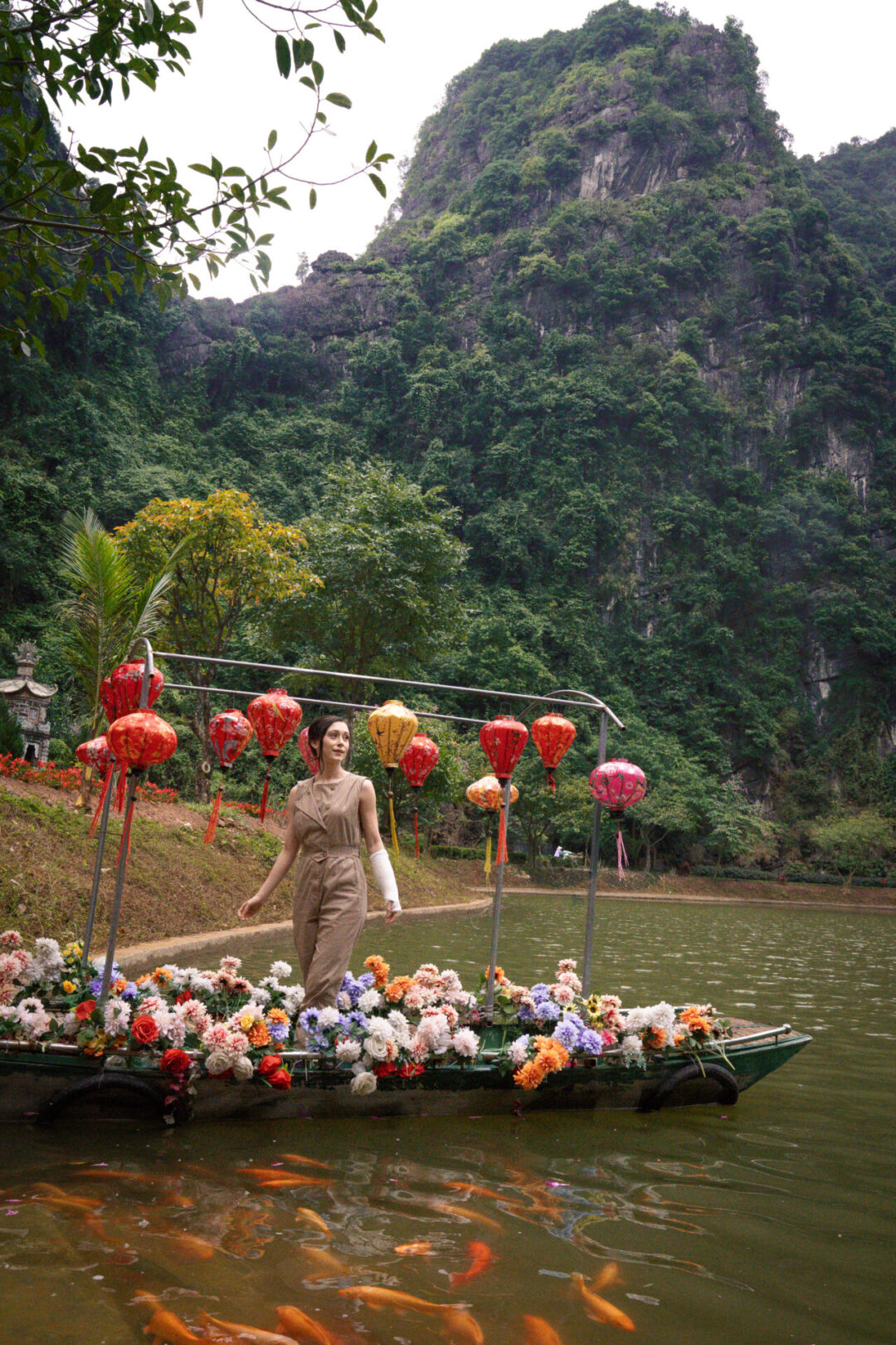 Travel Blogger Jordan Gassner looking out at the lake from a lantern and flower decorated boat inside Tuyet Tinh Coc in Ninh Binh, Vietnam