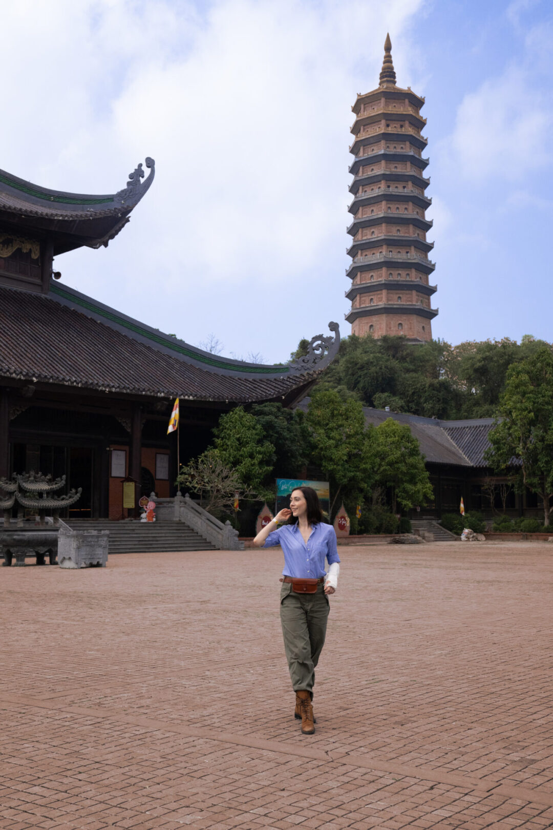 Travel Blogger Jordan Gassner smiling while walking through a courtyard outside a major temple in the Bai Dinh Complex in Ninh Binh, Vietnam