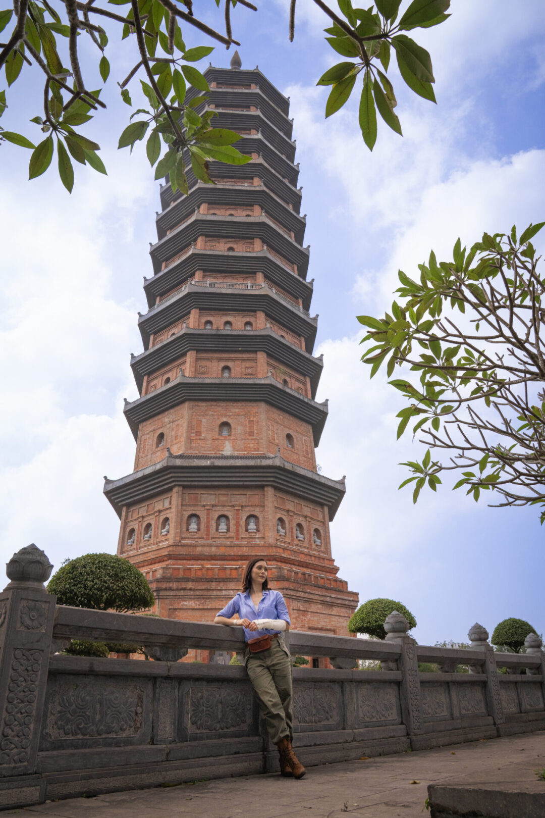 Travel Blogger Jordan Gassner leaning against a wall outside the pink stupa inside Bai Dinh Complex in Ninh Binh, Vietnam