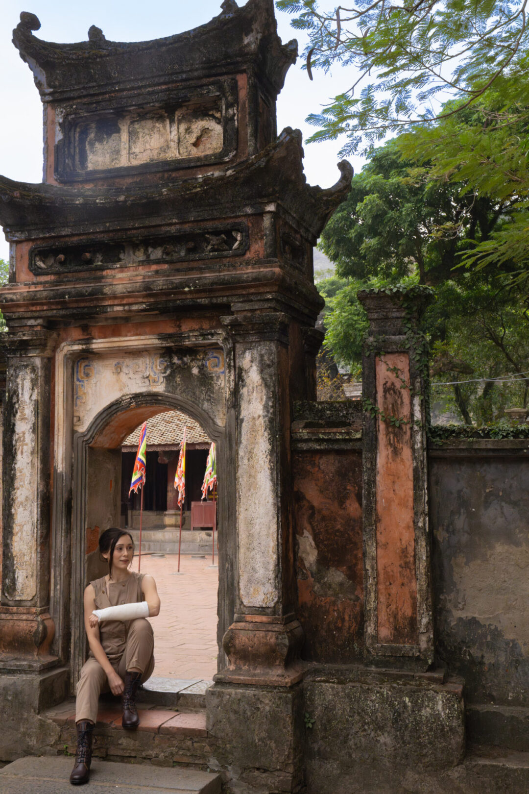 Travel Blogger Jordan Gassner sitting under an archway inside Hoa Lu Ancient Capital in Ninh Binh, Vietnam