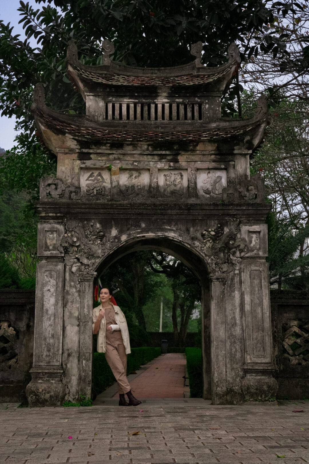 Things to do in Ninh Binh: Travel Blogger Jordan Gassner leaning against a stone archway at Hoa Lu Ancient Capital in Ninh Binh, Vietnam