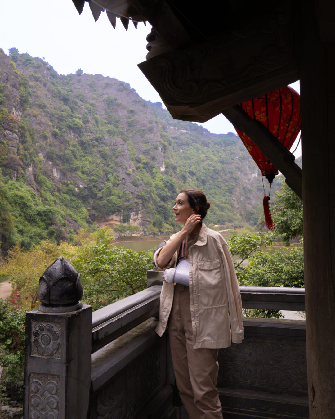 Travel Blogger Jordan Gassner standing underneath a small pagoda and hiding from the rain at Tuyet Tinh Coc in Ninh Binh, Vietnam