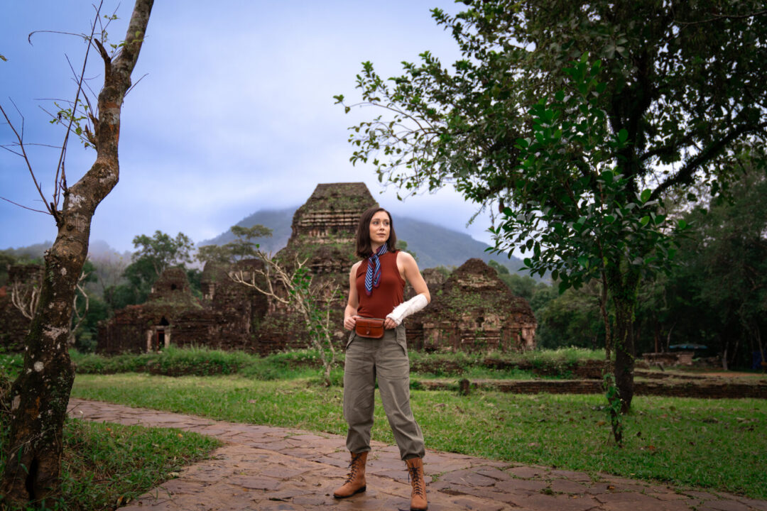 Travel Blogger Jordan Gassner standing confidently in front of ancient ruins in Vietnam with a cast and broken wrist