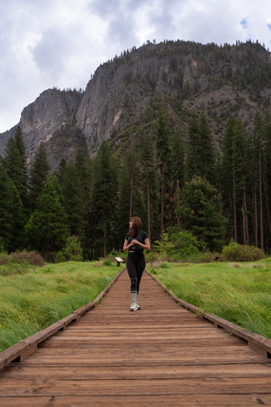 Travel Blogger Jordan Gassner walking along a wood boardwalk at Cook's Meadow Loop Trail in Yosemite, California