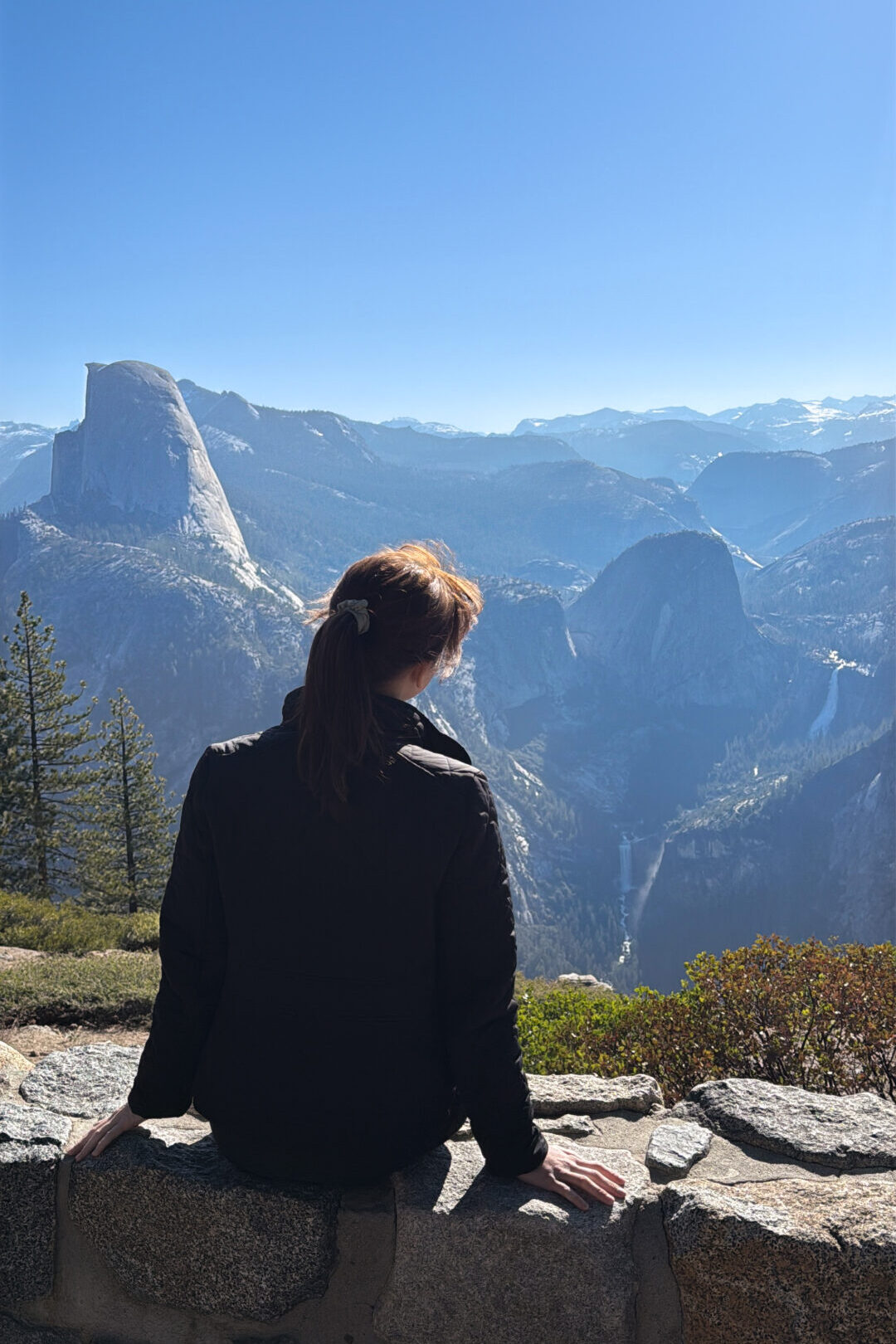 Travel Blogger Jordan Gassner looking out toward Vernal and Nevada Falls from Washburn Point on a Yosemite weekend trip