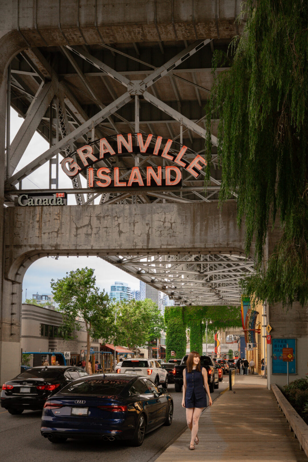 Travel Blogger Jordan Gassner walking along the sidewalk under the Granville Island sign in Vancouver, Canada