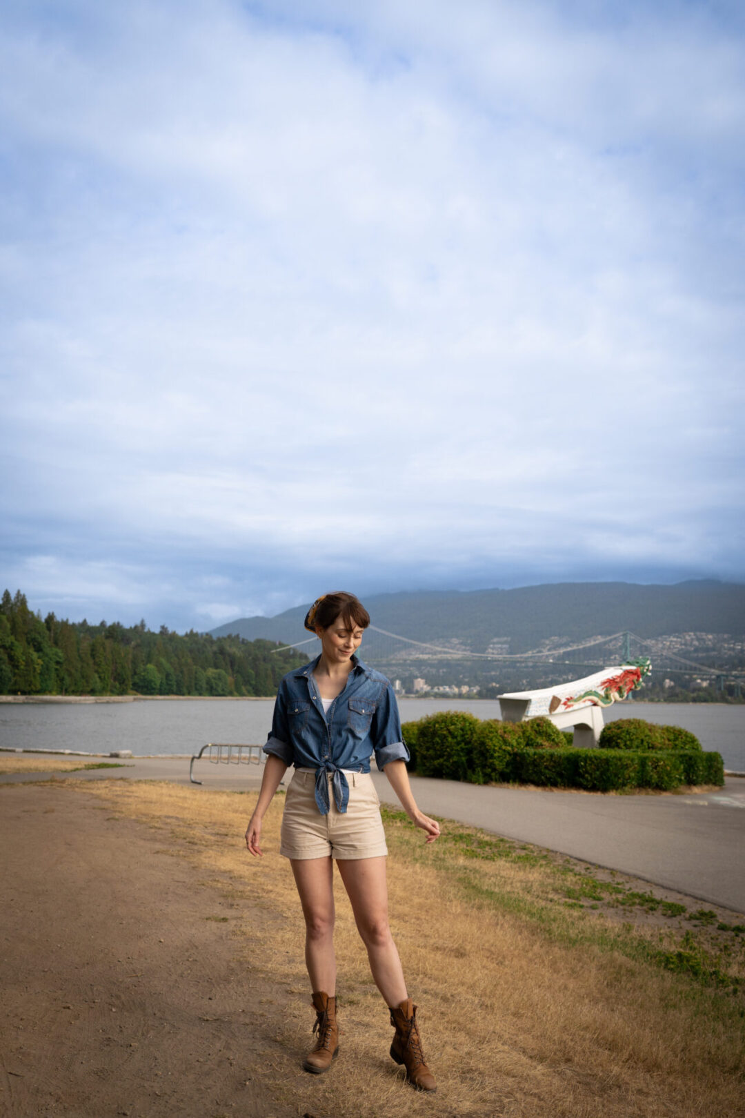 Travel Blogger Jordan Gassner standing near a staute overlooking the sea in Stanley Park located in Vancouver's West End