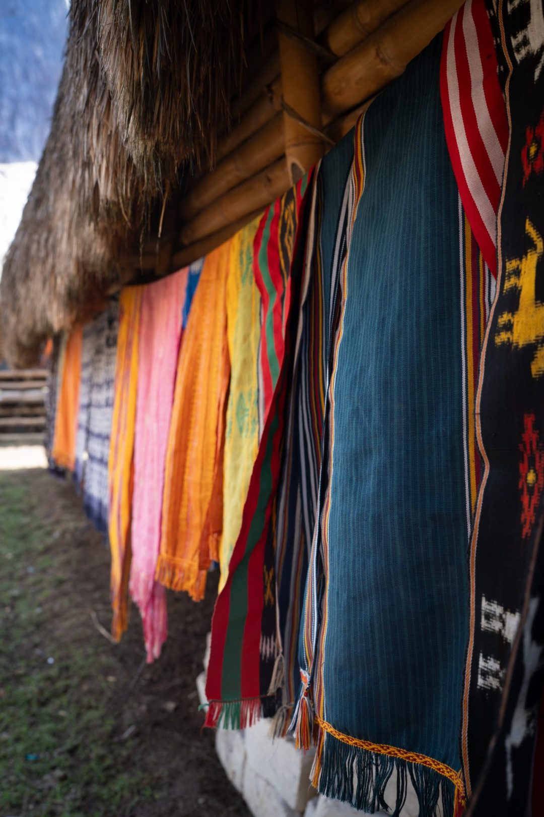 A row of colorful ikat textiles along the exterior of a home in Ratenggaro Village in Sumba, Indonesia