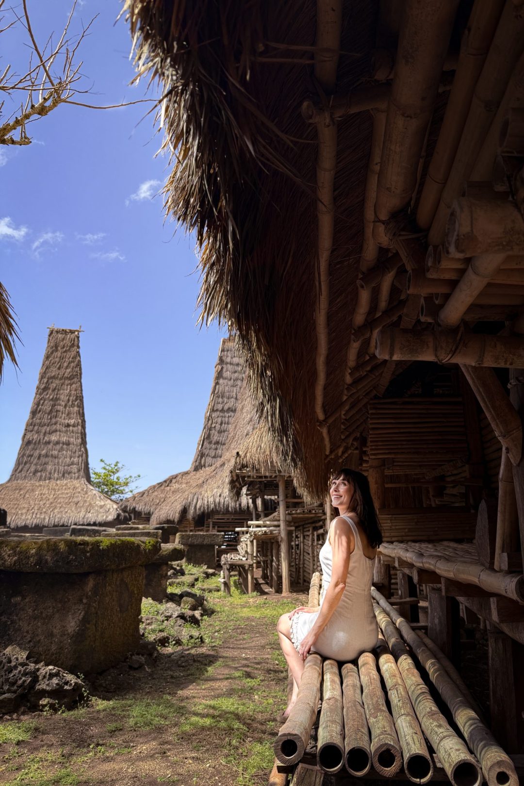 Travel Blogger Jordan Gassner smiling from the entrance to a traditional home in Sumba, Indonesia