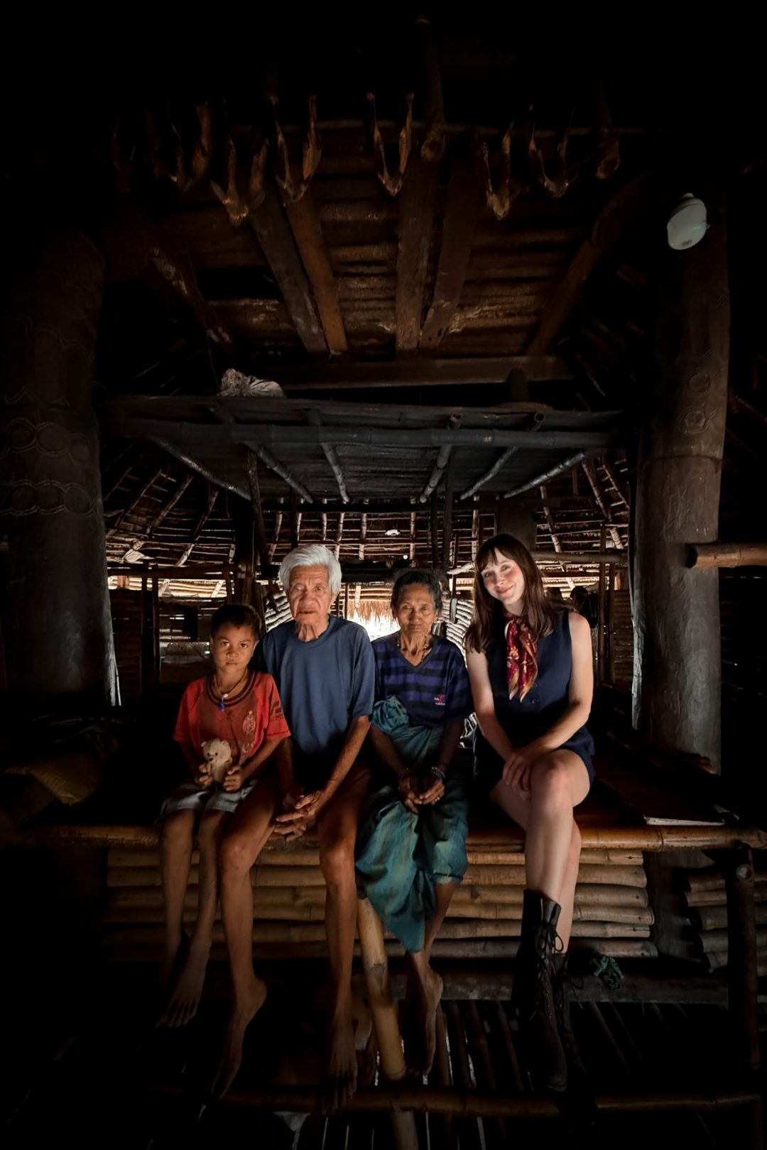 Travel Blogger Jordan Gassner smiling with a family inside their traditional house (Uma Bokulu) in Waikaroko, one of the traditional villages in Sumba, Indonesia