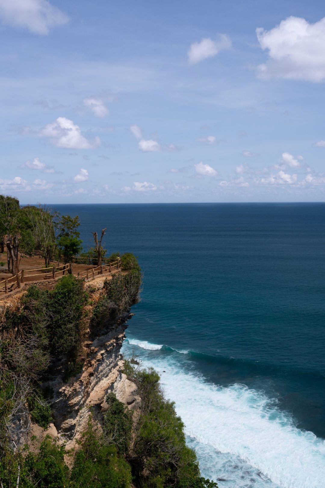 Travel Blogger Jordan Gassner standing far away along the edge of a cliff in Bali, Indonesia