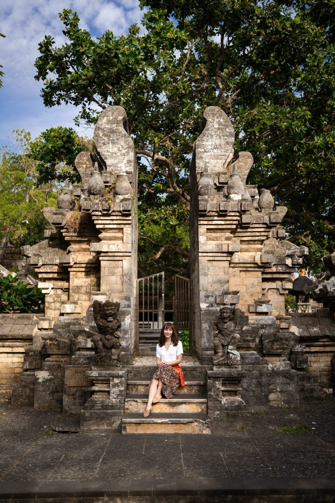 Travel Blogger Jordan Gassner sitting along a few steps at Uluwatu Temple in Bali, Indonesia