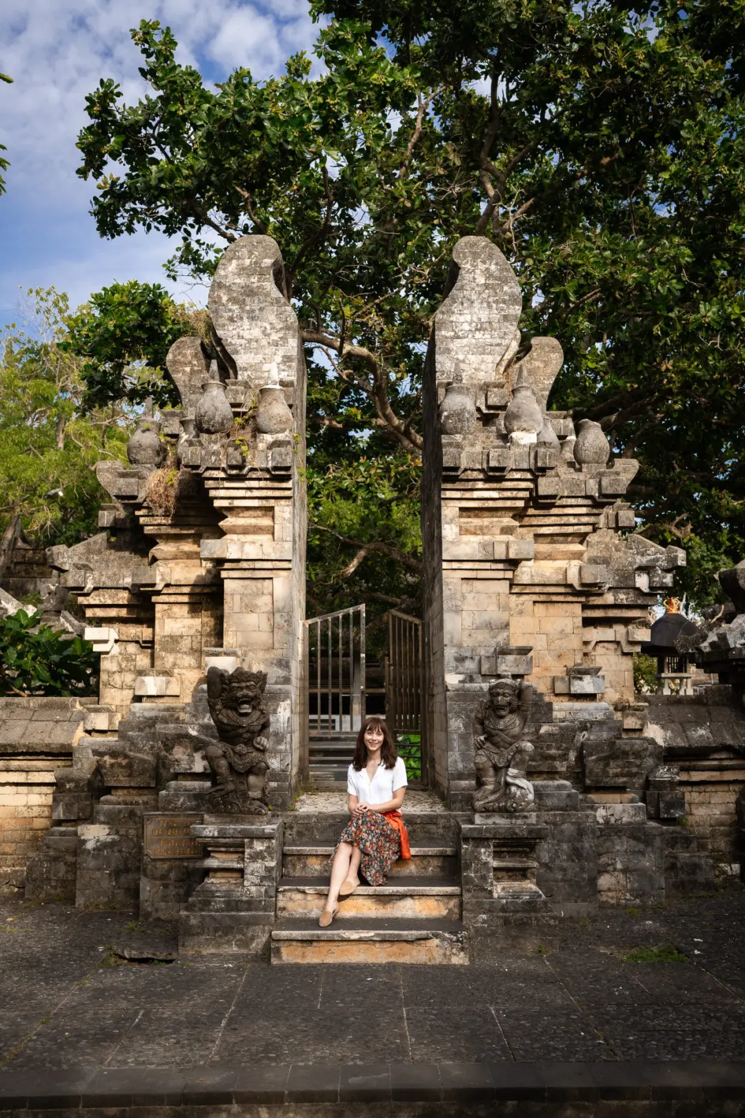 Travel Blogger Jordan Gassner sitting along a few steps at Uluwatu Temple in Bali, Indonesia