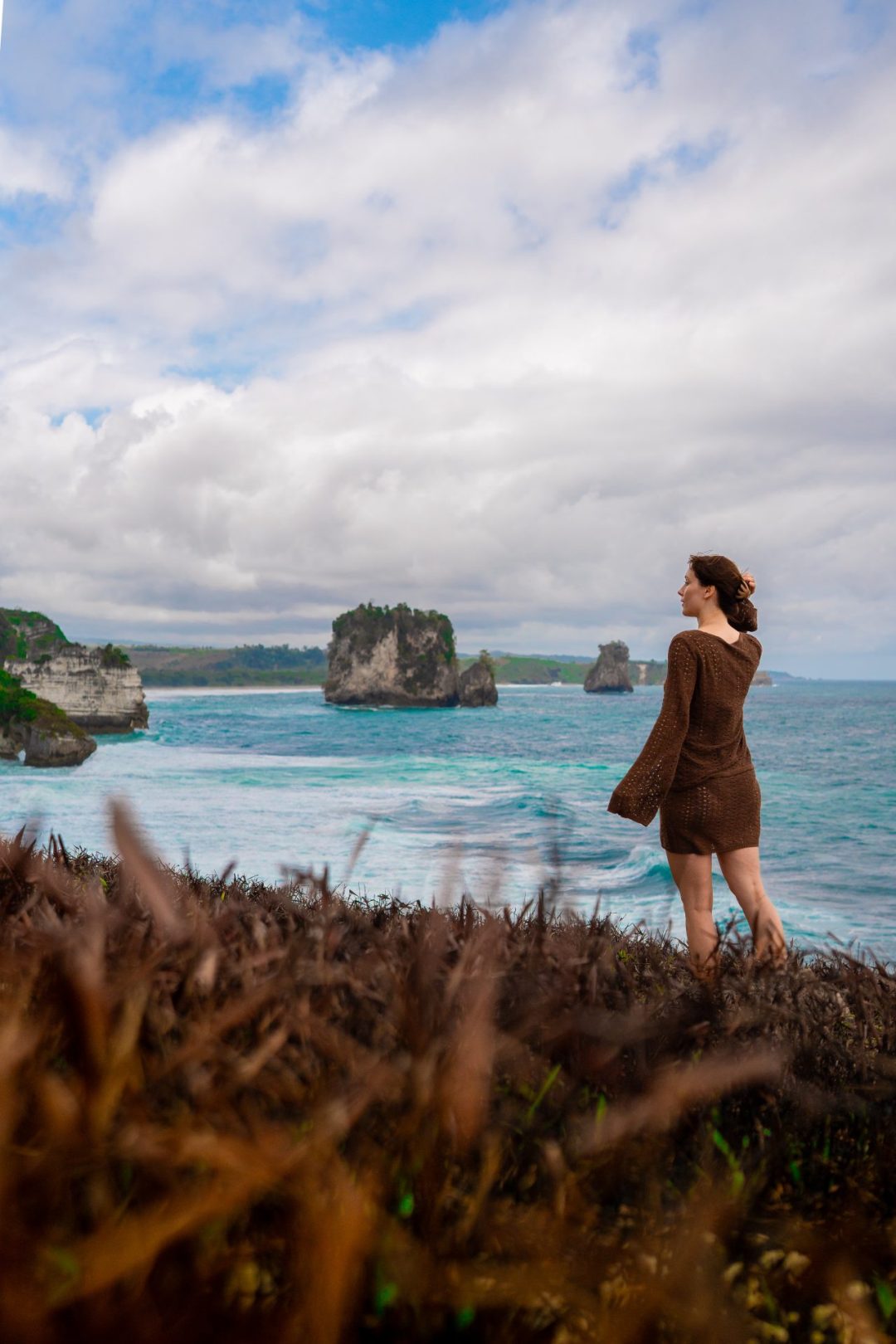 Travel Blogger Jordan Gassner standing on a cliff overlooking a turquoise ocean in SUmba, Indonesia