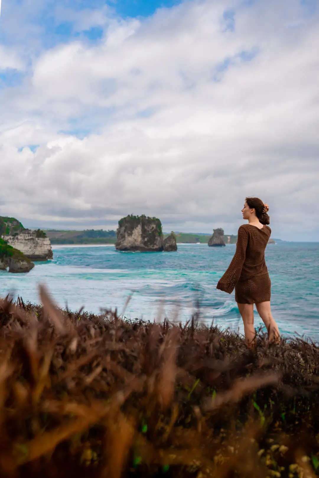 Travel Blogger Jordan Gassner standing on a cliff overlooking a turquoise ocean in SUmba, Indonesia