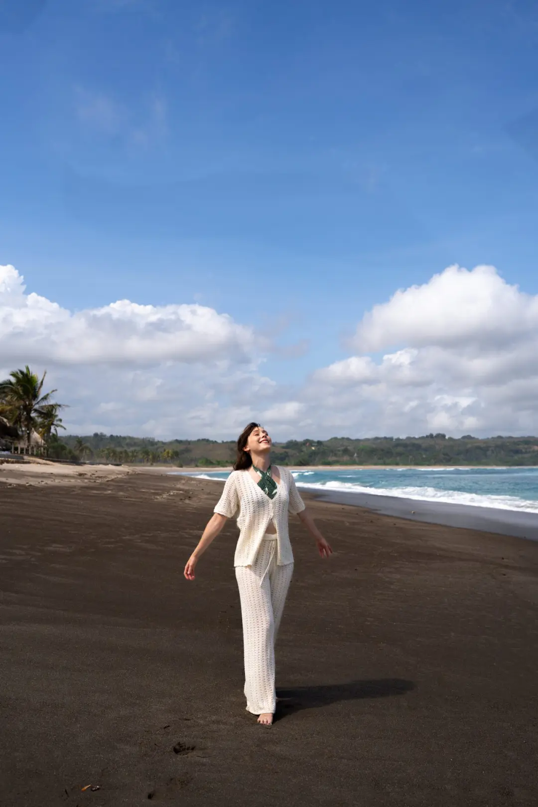 Travel Blogger Jordan Gassner looking up and smiling from the black sand along Kerewe Beach in Sumba, Indonesia