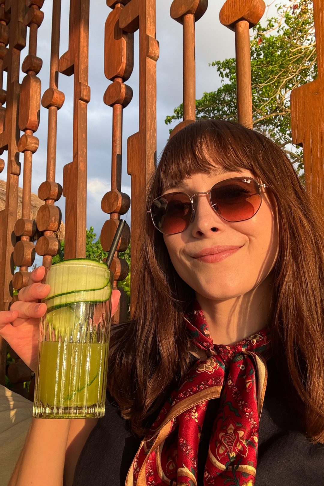 Travel Blogger Jordan Gassner smiling and holding a green juice with cucumbers from the Cap Karoso Beach Club in Sumba, Indonesia